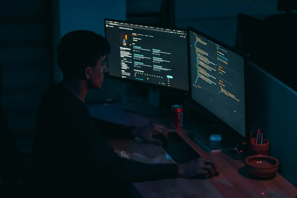 Développeur devant deux écrans de code, en train de mettre au point un flux automatisé